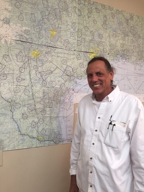 Flight instructor in a white shirt standing in front of a San Antonio aviation sectional chart