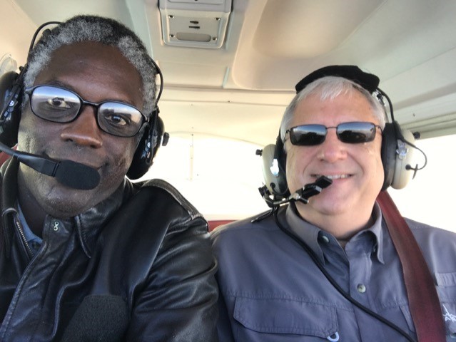 Two pilots sit in small plane, smiling